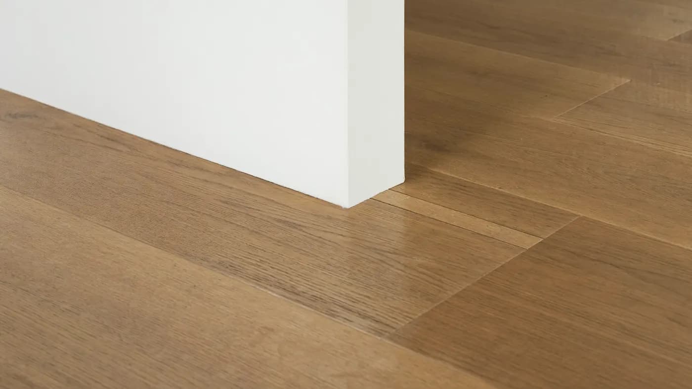 Montierte Sockelleiste entlang einer Laminatwand – Motiv zur Längenberechnung